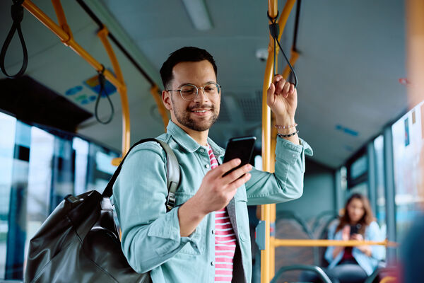 Mann mit Smartphone in der Hand steht im Bus